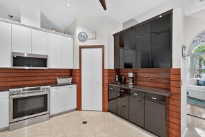 A modern kitchen with white cabinets, a built-in oven, a microwave, and a coffee maker.