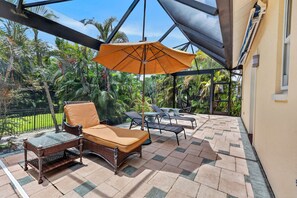A covered outdoor seating area with wicker furniture and a large umbrella.