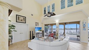 A spacious living room with a white sectional sofa, a television, and a view of the outdoors.