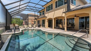 A swimming pool with clear water, surrounded by outdoor seating and a covered patio area.