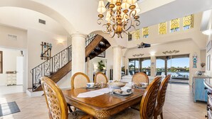 A spacious dining area with a large wooden table, ornate chairs, and a chandelier.