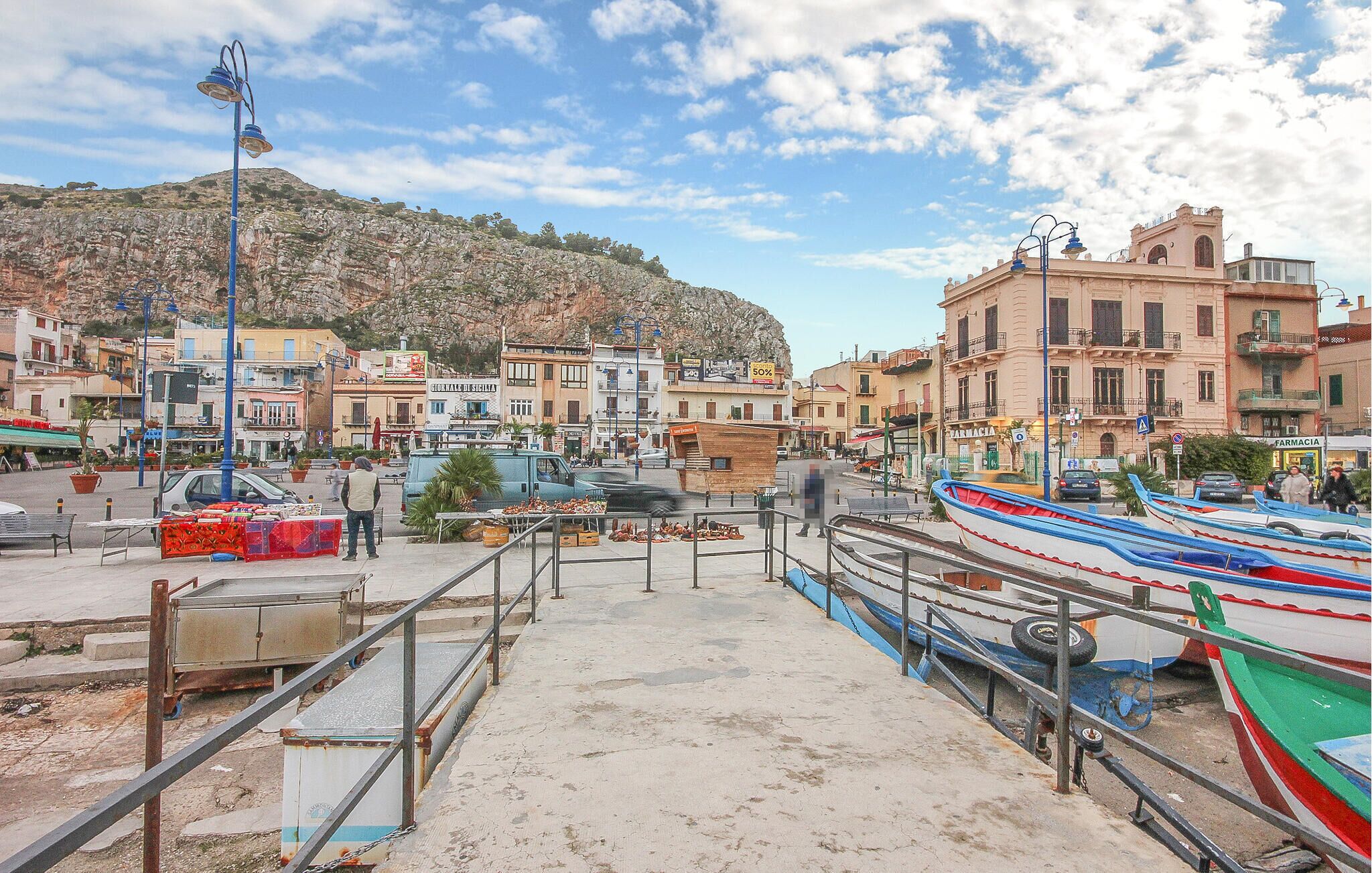 A coastal town with colorful boats docked, a pharmacy, and buildings with balconies.