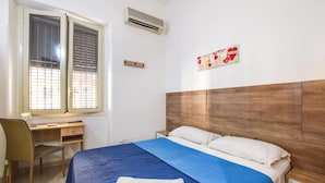 A bedroom with a bed, a desk, and a chair.