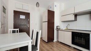 Une cuisine moderne avec des meubles blancs, une table à manger en bois et un four encastré.