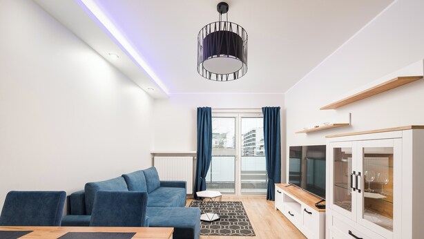 A modern living room with a blue sofa, wooden coffee table, and a TV cabinet. - Racjonalizacji Stylish Apartment (Warszawa)