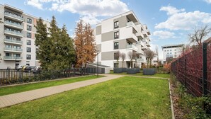 A modern apartment complex with multiple balconies, a paved walkway, and a grassy area. - Racjonalizacji Stylish Apartment (Warszawa)