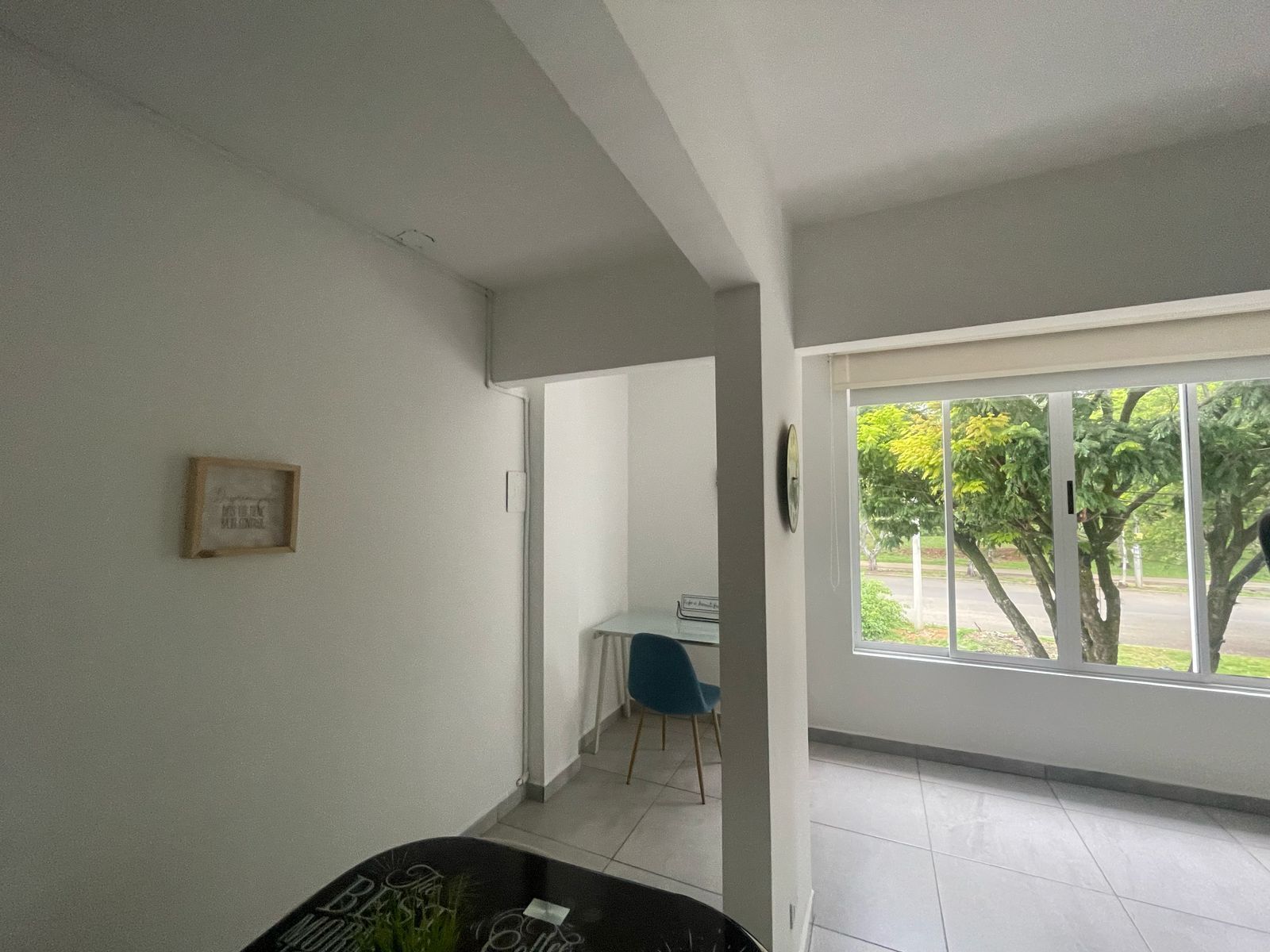 Una habitación amplia con un gran ventanal, un escritorio y una silla.