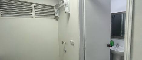 A small, white bathroom with a shower, a toilet, and a sink.