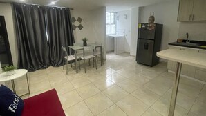 A modern kitchen with a refrigerator, a dining table with chairs, and a window. - Ingenio Park 83 - Apartaestudios (Cali)