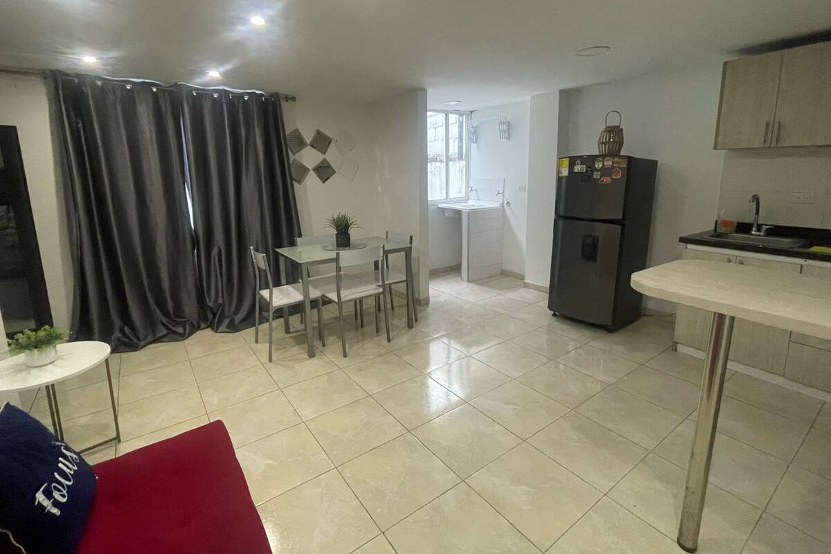 A modern kitchen with a refrigerator, a dining table with chairs, and a window.