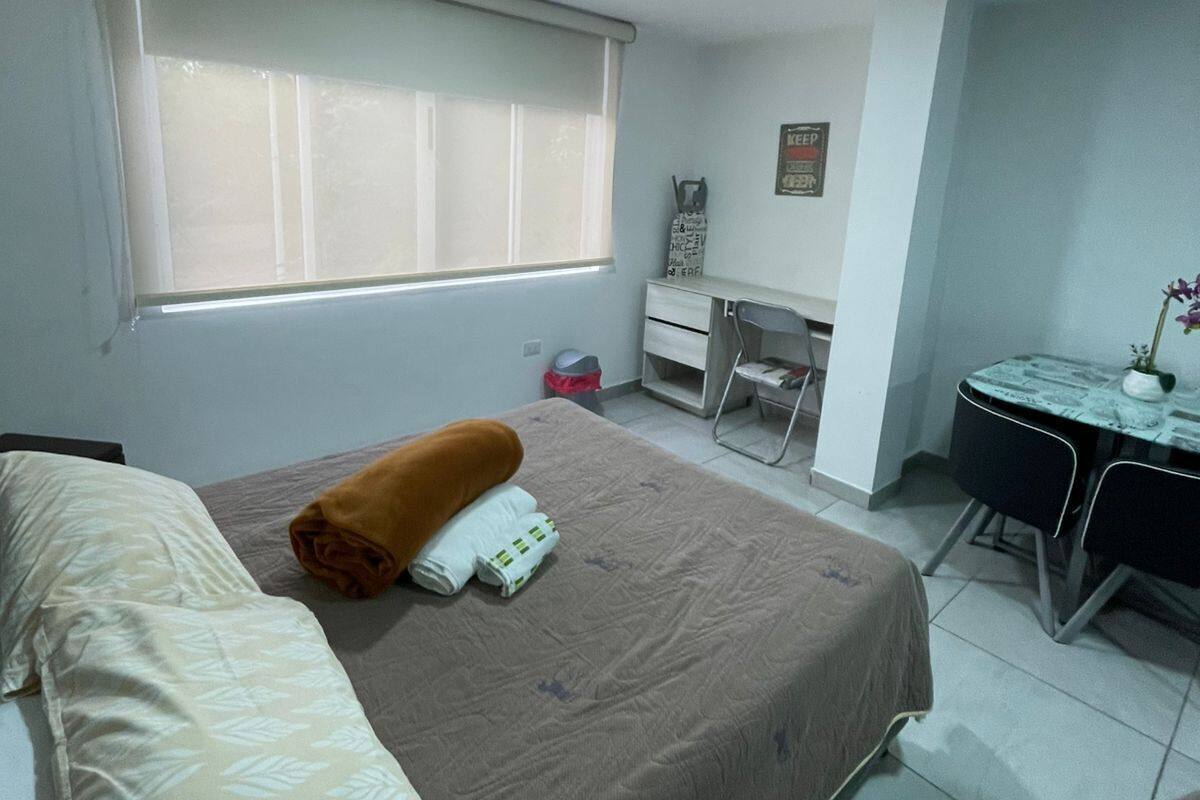 A hotel room with a bed, a desk, a chair, and a window.