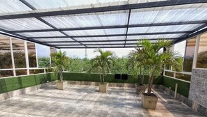 A covered outdoor area with a tiled floor, potted plants, and a glass ceiling. - Ingenio Park 83 - Apartaestudios (Cali)