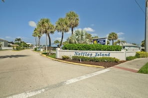 A sign for 'Nettle's Island Real Estate' with palm trees and a clear sky.