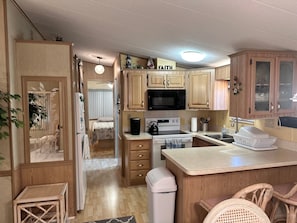 Una cocina compacta con gabinetes de madera, un microondas, una estufa y un lavabo.