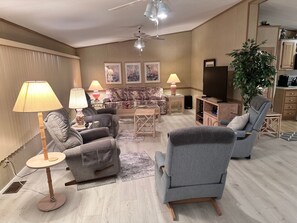 Olohuoneessa on sohva, nojatuoleja, sohvapöytä, televisio ja kattotuuletin.