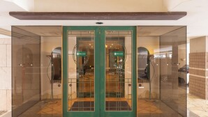 L’entrée d’un hôtel, avec une porte en verre et un cadre vert.