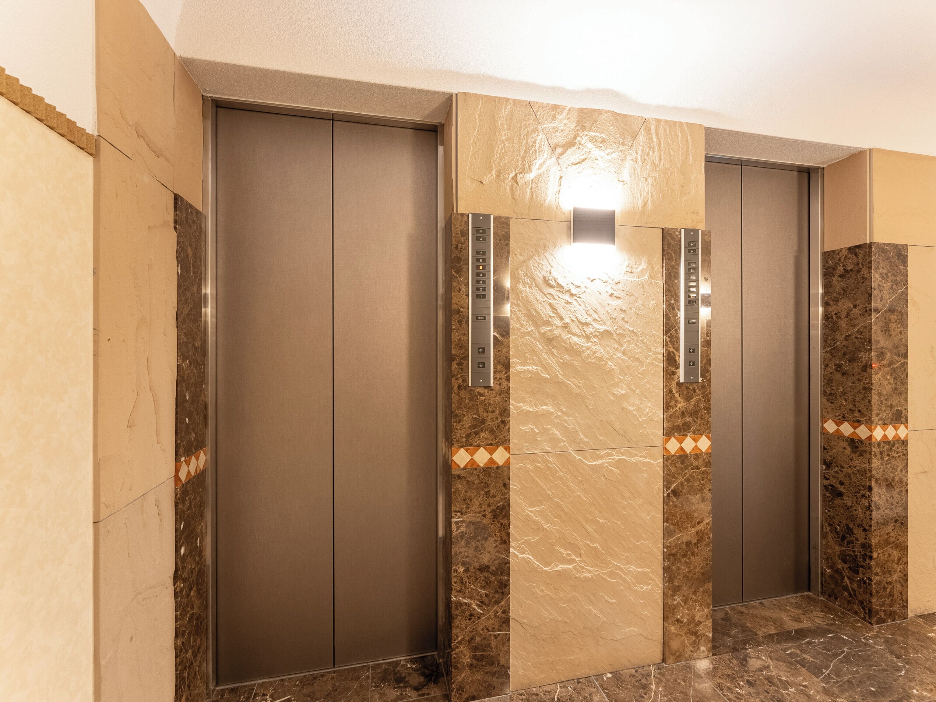 A modern elevator with a marble finish and control panel.
