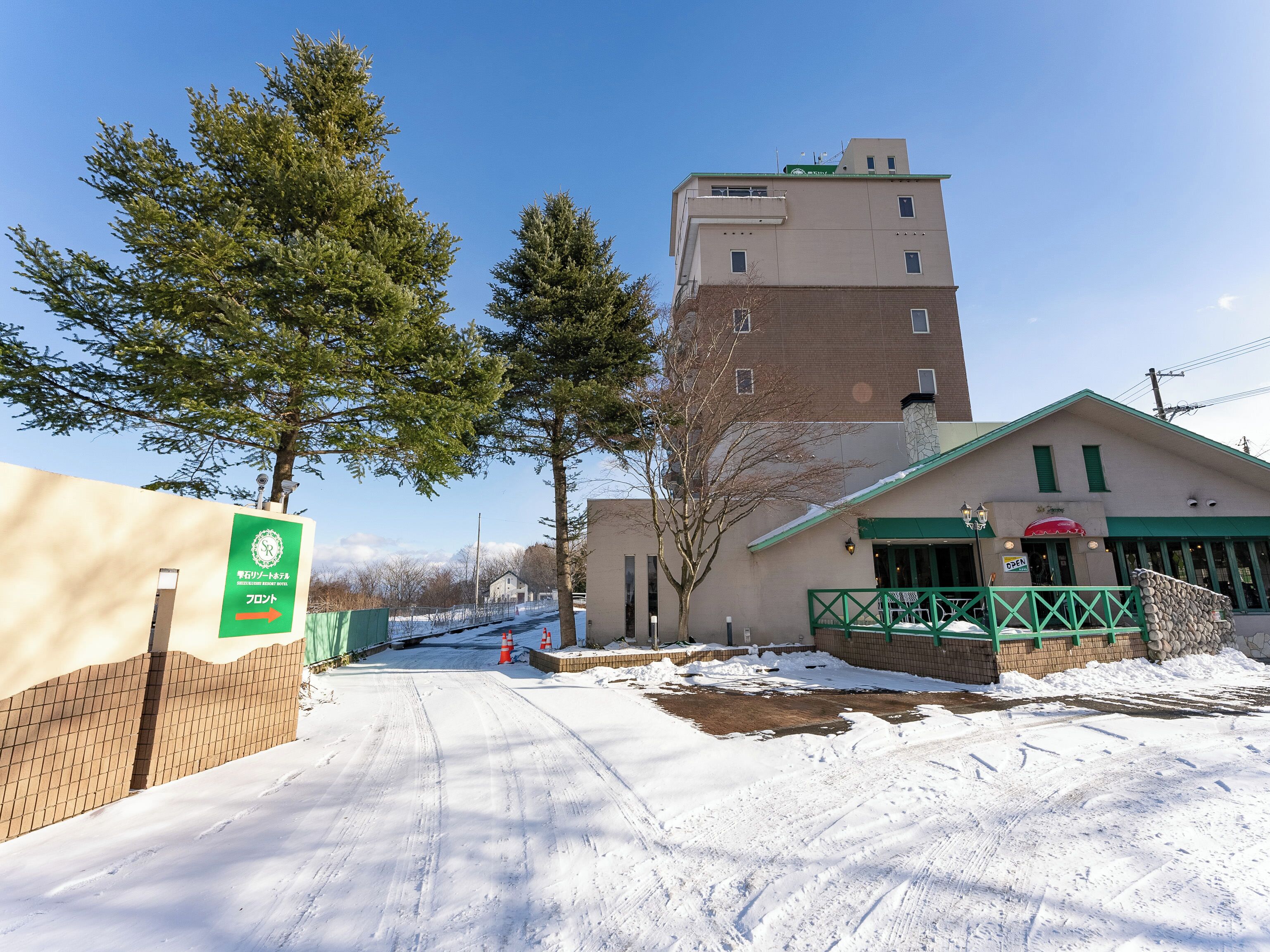 Un edificio con ingresso verde e un cartello che indica un'area di parcheggio.