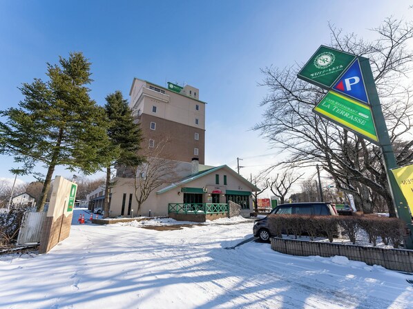 A hotel with a parking sign, a restaurant named "La Terrasse," and a building with a green roof.