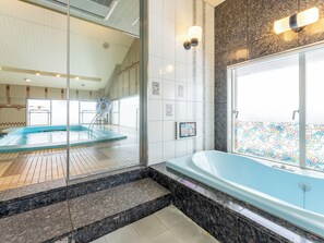 A modern indoor swimming pool with a glass wall, a separate jacuzzi area, and a tiled floor. - Tabist Shizukuishi Resort Hotel (Shizukuishi)