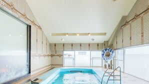 Une piscine intérieure à l’eau claire, avec des murs carrelés et une bouée de sauvetage.