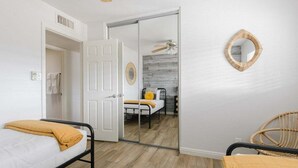 Ein Schlafzimmer mit Bett, Stuhl, Kleiderschrank und Spiegel.
