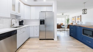 Eine moderne Küche mit weißen Schränken, einem Edelstahlkühlschrank und einer Holz Arbeitsplatte.