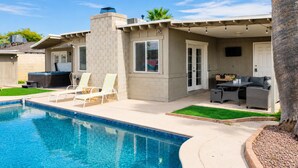 Ein Poolbereich mit Wohnbereich, ausgestattet mit Whirlpool, Liegestühlen und einer Terrasse mit Gartenmöbeln.