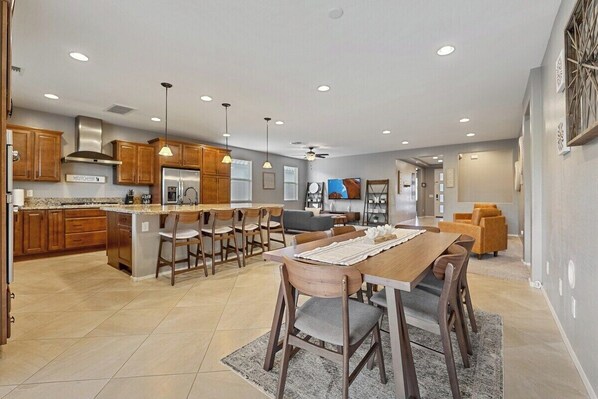 A spacious kitchen with wooden cabinets, a central island, and pendant lighting.
