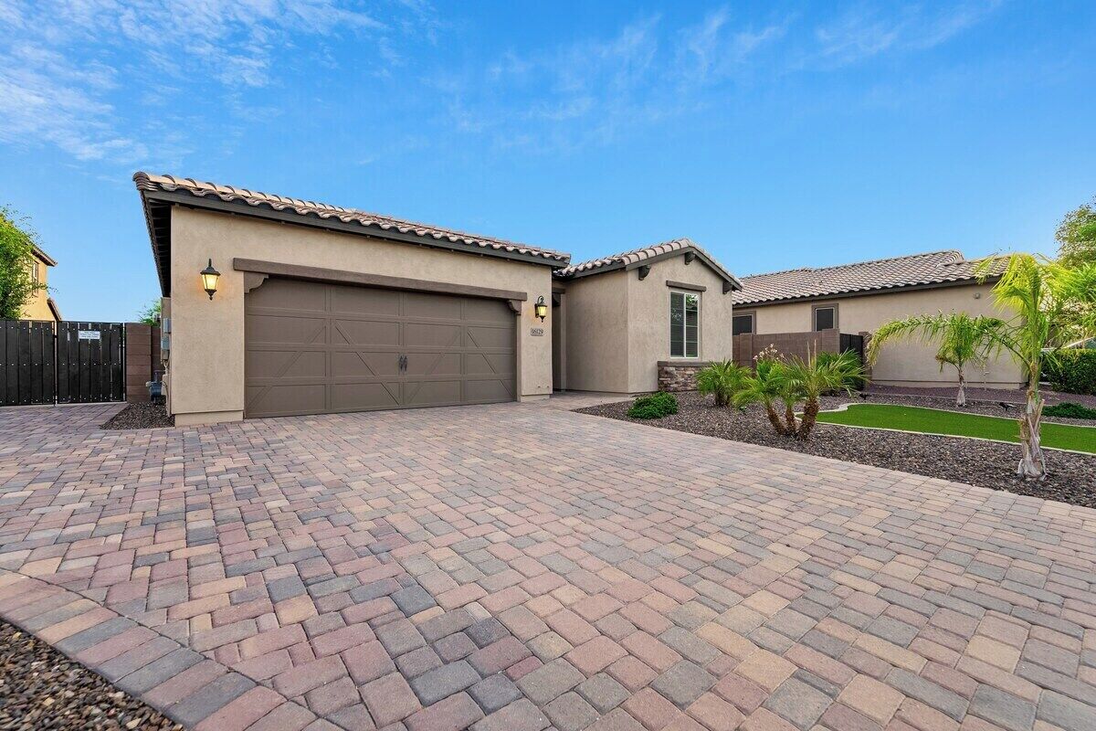 A residential house with a garage, paved driveway, and small landscaped garden.
