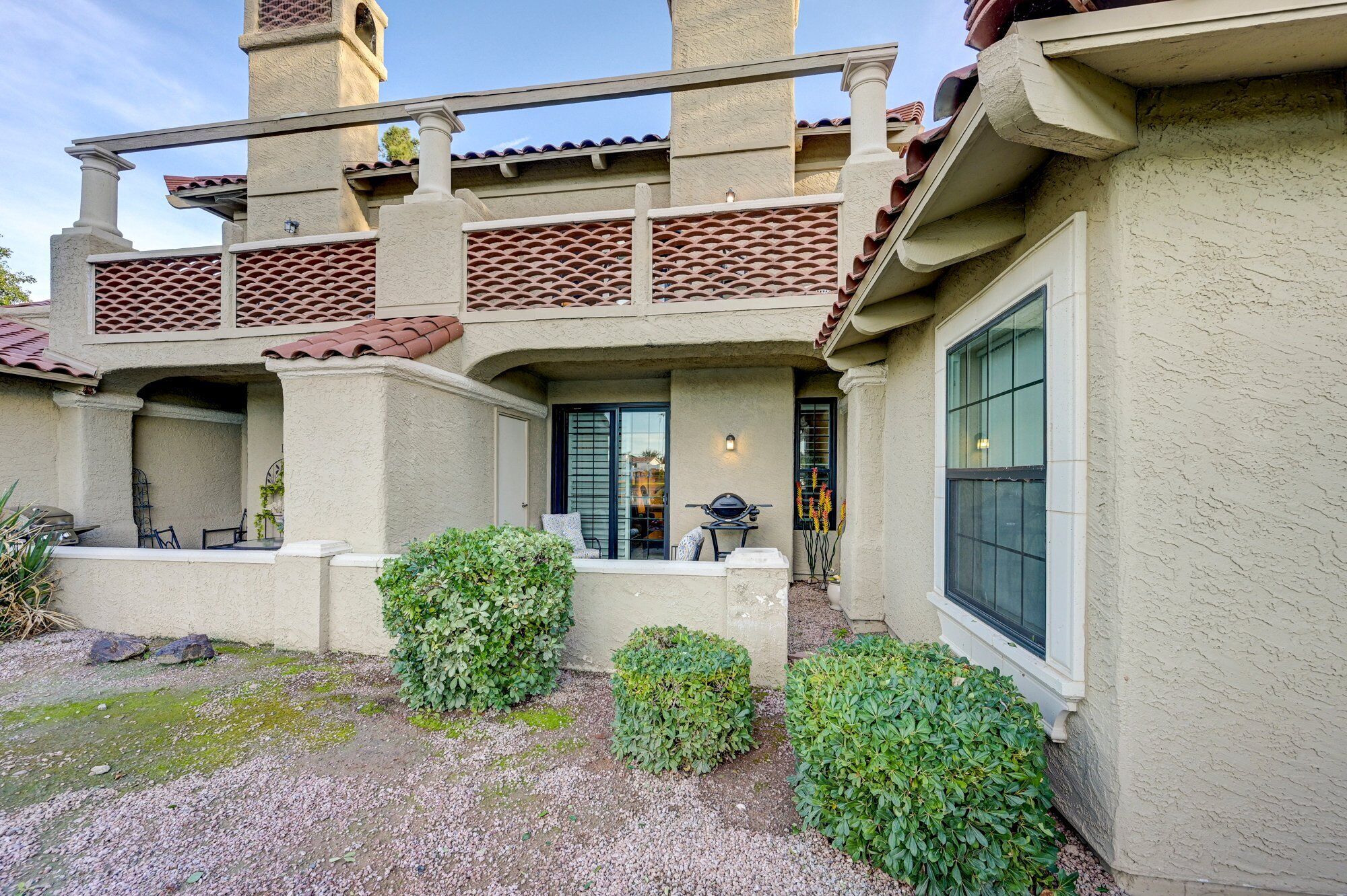 Una casa con un patio, una zona de estar techada y un ventanal grande.
