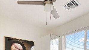 A bedroom with a bed, a ceiling fan, a window with blinds, and a wall-mounted air vent. - Home Run! Walk to Chase Field | 2BR Summer Stay in Downtown PHX (Phoenix)
