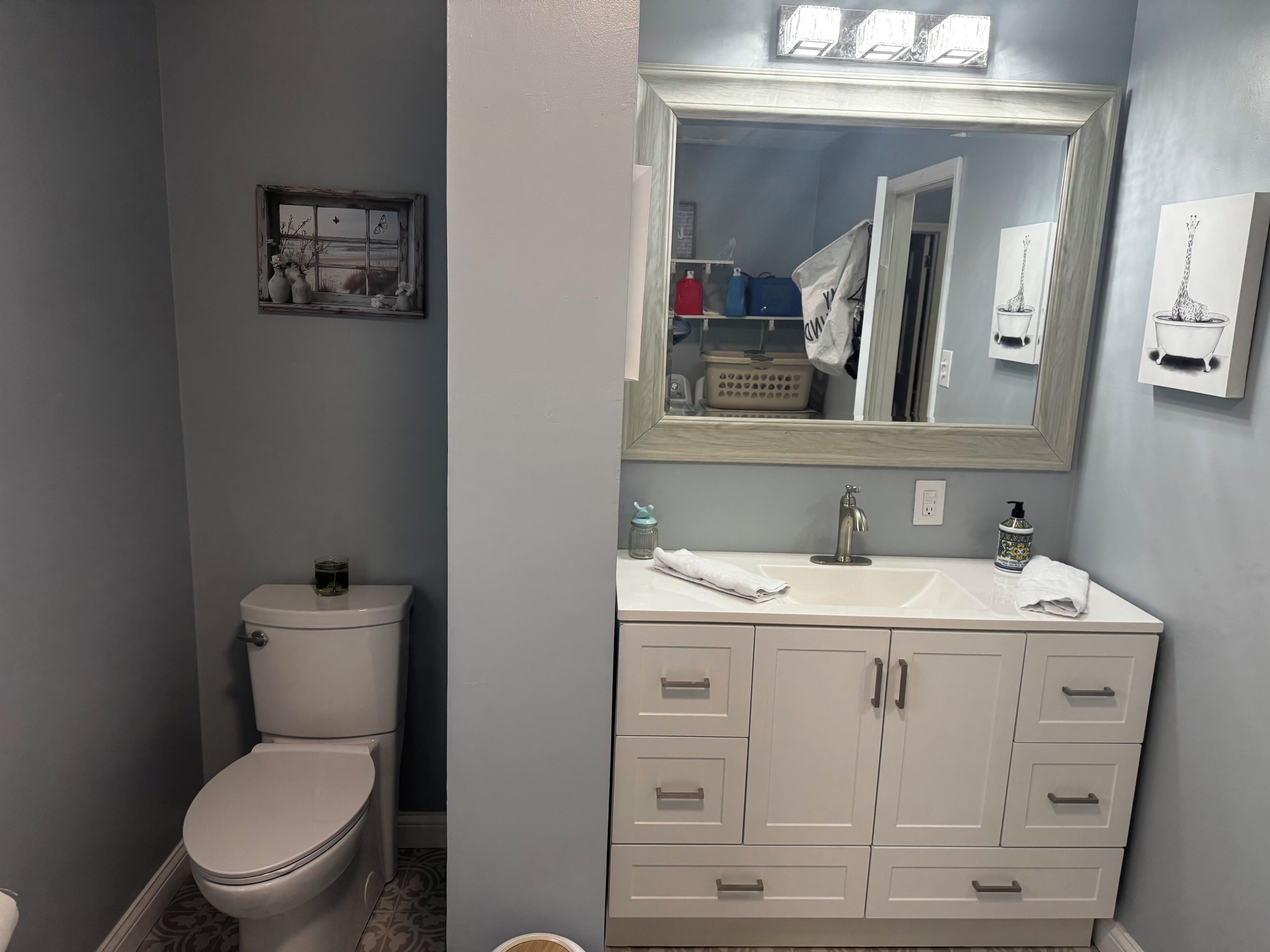 Een badkamer met toilet, een wastafel met spiegel en kastjes.