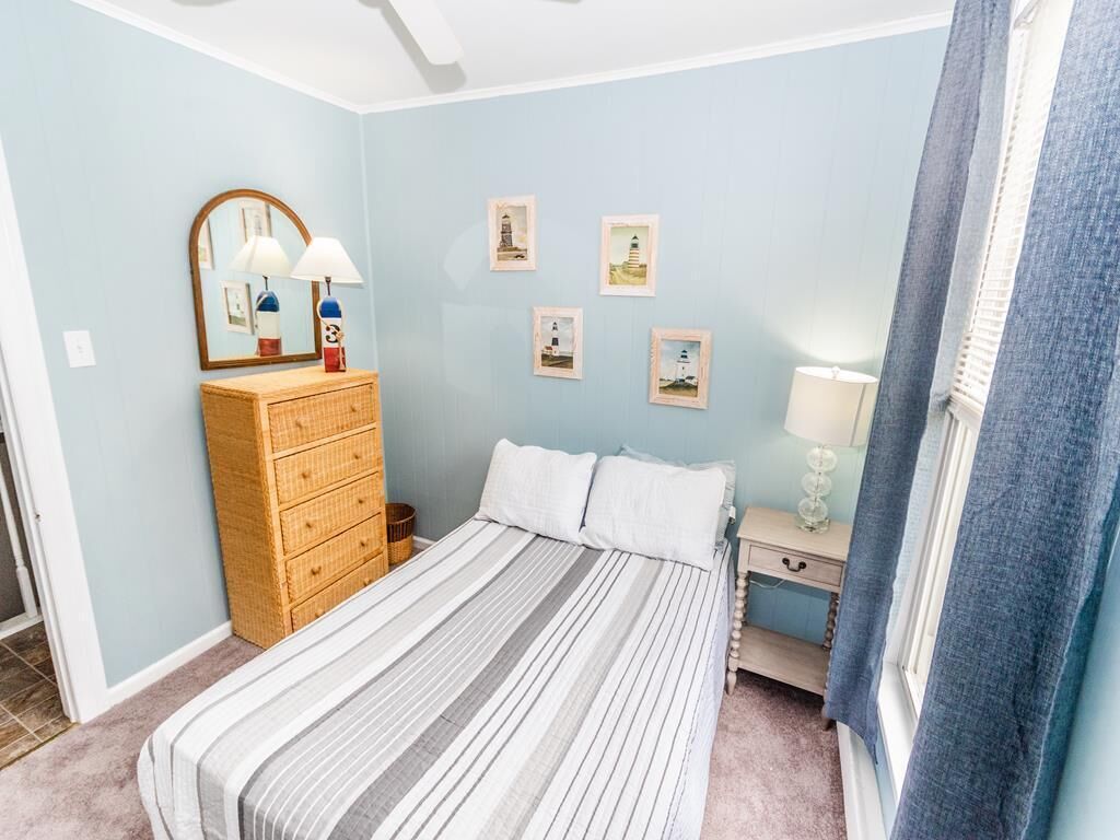 Un dormitorio con cama, cómoda, mesita de noche, lámpara y decoración en la pared.