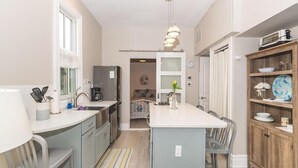 Een moderne keuken met een centraal eiland, grijze kasten en een houten kast met servies.