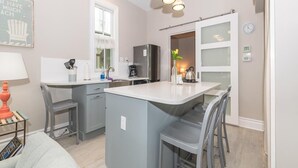 Een moderne keuken met grijze kastjes, een centraal eiland, hanglampen en uitzicht op de eetruimte.
