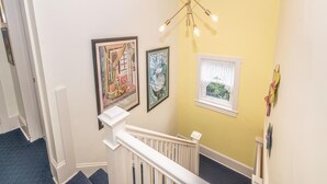 A staircase with a white railing, a yellow wall, and a ceiling light fixture.