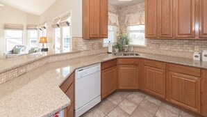A kitchen with wooden cabinets, a dishwasher, and a tiled backsplash. - Top Floor Deck w/ Ocean View | Beach Block House (Cape May)