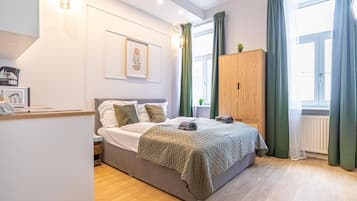 Ein Schlafzimmer mit Bett, Holzschrank, Heizkörper und einem Fenster mit Vorhängen.