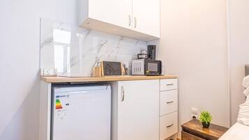 Eine kleine Küchenzeile mit einem Kühlschrank, einer Mikrowelle und einer Kaffeemaschine auf einer Holz Arbeitsplatte.