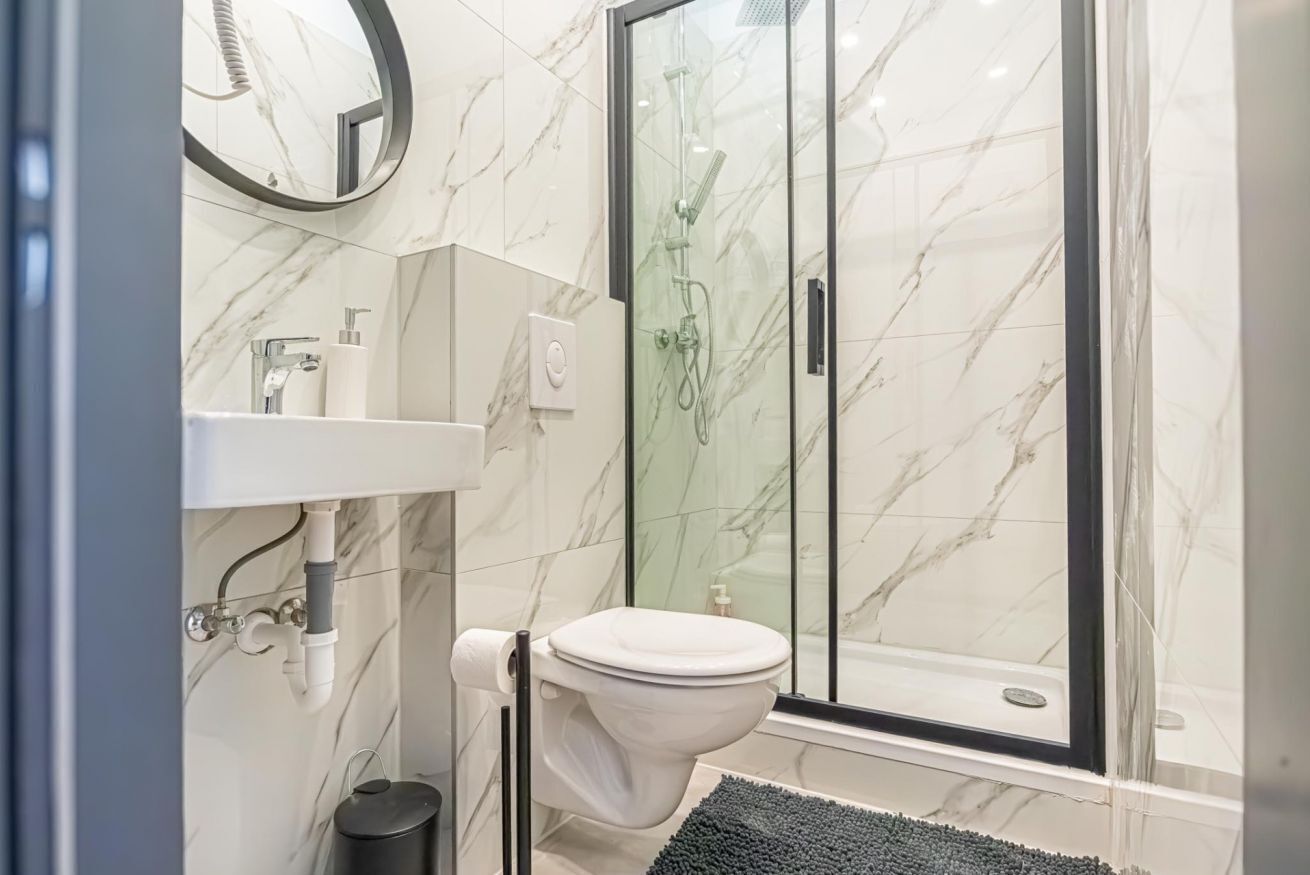 A bathroom with a toilet, sink, and glass shower enclosure.