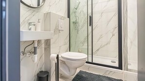 A bathroom with a toilet, sink, and glass shower enclosure. - Cozy & Quiet Studio in Vienna’s 12th District (Vienna)