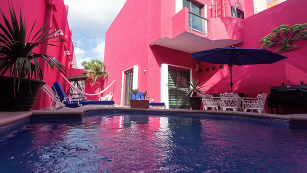 A pink building with a swimming pool, lounge chairs, and potted plants. - Casa 53 Marichuy Mexican Style with private pool! (Cancún)