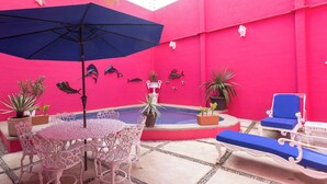 A pink-themed outdoor area with a pool, lounge chairs, and decorative fish on the wall. - Casa 53 Marichuy Mexican Style with private pool! (Cancún)