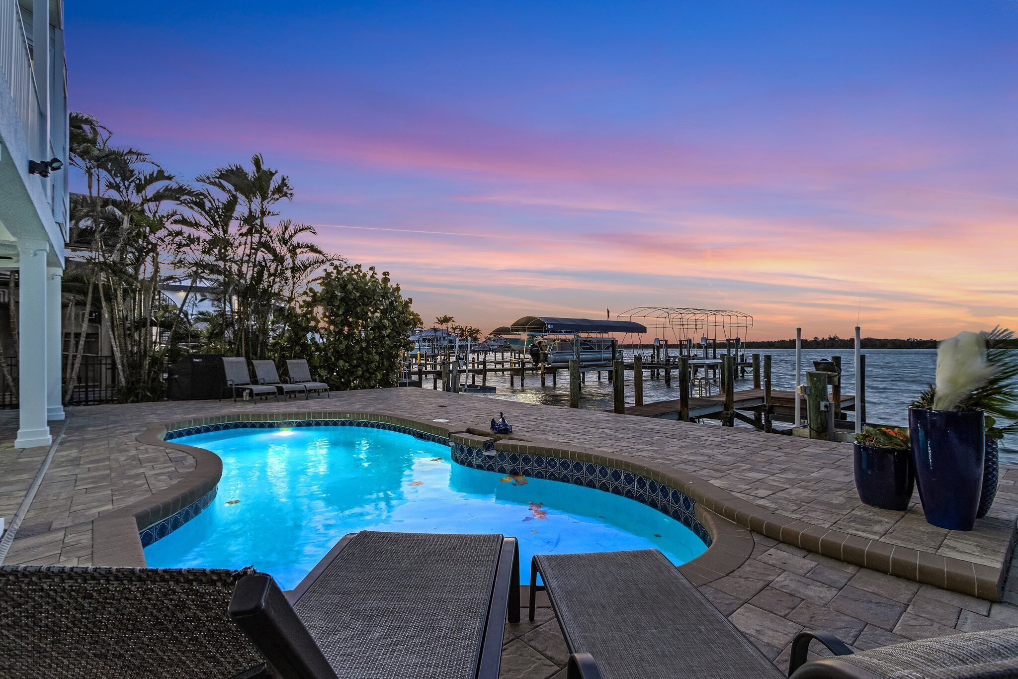 A swimming pool with lounge chairs, a dock, and a view of the water.