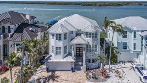 Ein Küstenhaus mit einer großen Garage, einer überdachten Veranda und Blick auf das Wasser.