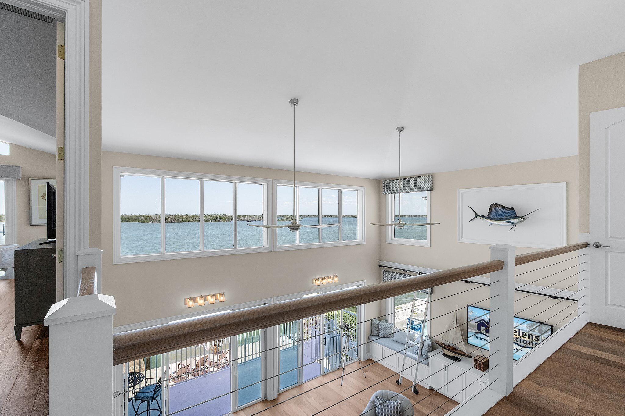 A spacious living area with large windows overlooking a body of water, a balcony with outdoor seating, and a modern interior design.