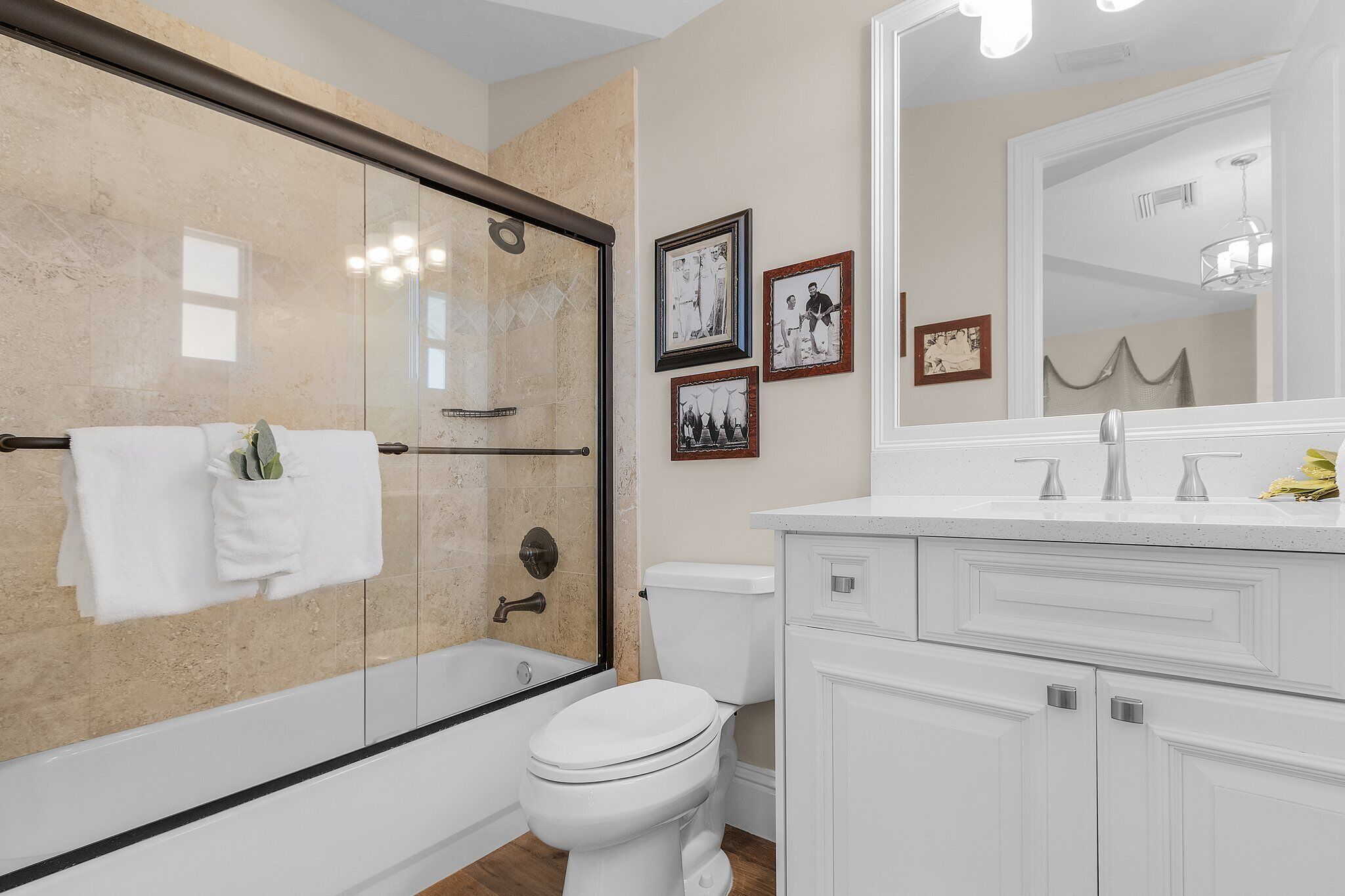 A bathroom with a glass-enclosed shower, a white toilet, and a vanity with a mirror.