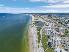 An aerial view of a coastal city with a beach, residential buildings, and a marina.