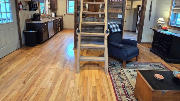 Un interior rústico con una escalera de madera, una cocina con electrodomésticos modernos y una zona de estar acogedora.